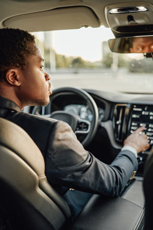 Black businessman inside car using car panelの写真素材