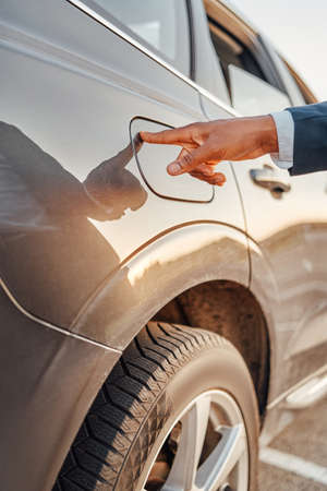 Shot of businessman with his finger on fuel tank of carの写真素材
