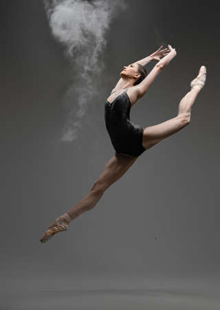 Professional ballerina dancing in studio against gray backgroundの写真素材