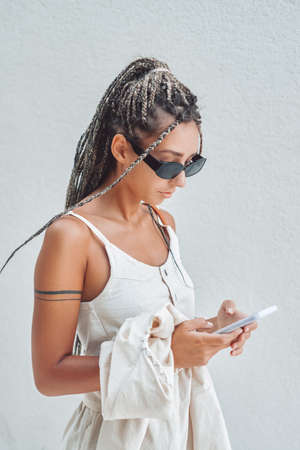 Trendy woman using her smartphone against wallの写真素材