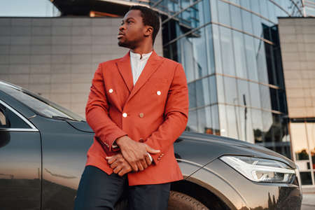 Confident black businessperson posing leaning his carの写真素材
