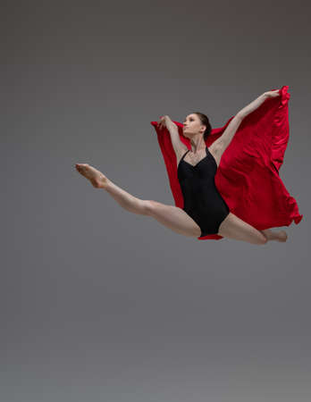 Jumping ballerina in tutu holding red silkの写真素材