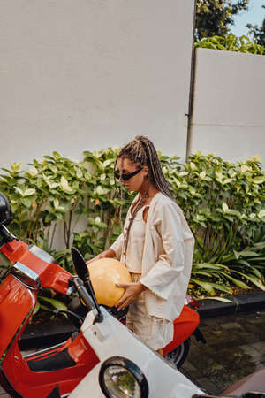 Woman with helmet and scooter outside in bali