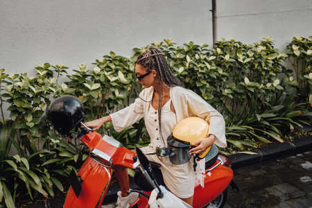 Woman with helmet and scooter outside in baliの写真素材