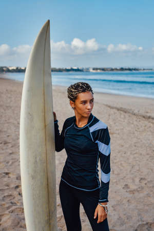 Woman with dreadlocks and surfboad on beachの写真素材