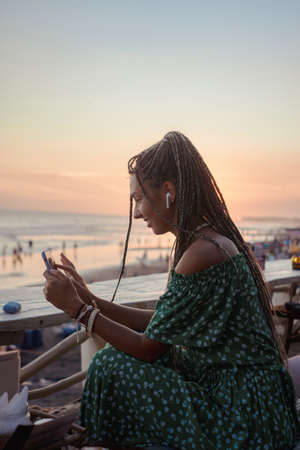 Joyful woman on beach with earphones and phoneの写真素材