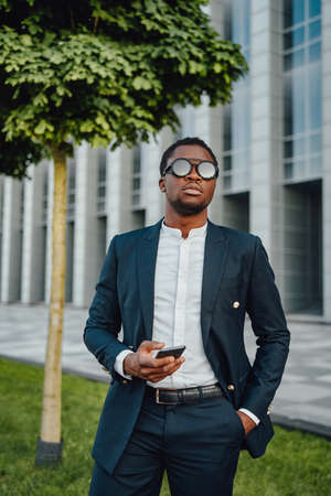 Confident african businessperson weared in suit with phoneの写真素材