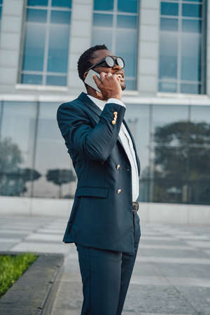 Black entrepreneur talking on smartphone against city buildingの写真素材