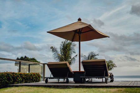 Shot of two sun loungers with umbrella against seascape