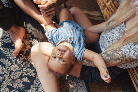 Happy little girl playing with her father and mother at home