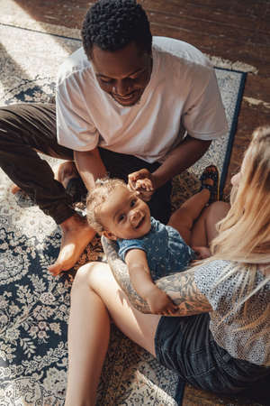 Shot of young mixed race family in bedroom in daytimeの写真素材