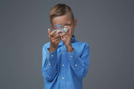 Preteen kid posing with brilliant against gray background