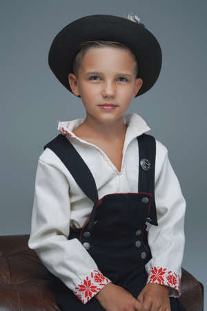 Shot of stylish young boy with hat sitting on chair
