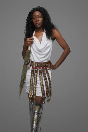 African woman with wavy hairs holding gladius isolated on grayの写真素材