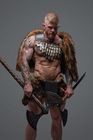Scandinavian vandal with fur and armor holding two axesの写真素材