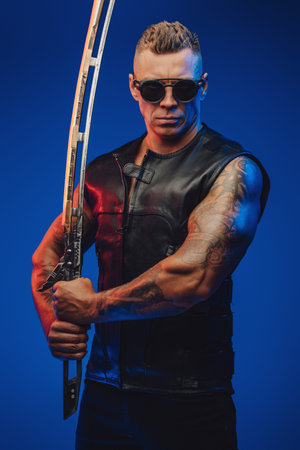 Muscular guy in cyberpunk style with sword against blue backgroundの写真素材