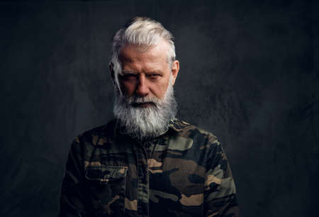 Elderly man dressed in camouflage suit against dark backgroundの写真素材