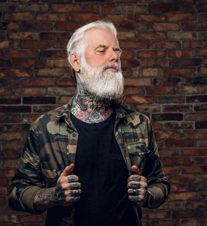 Stylish grandfather with tattooed body dressed in camouflage jacketの写真素材