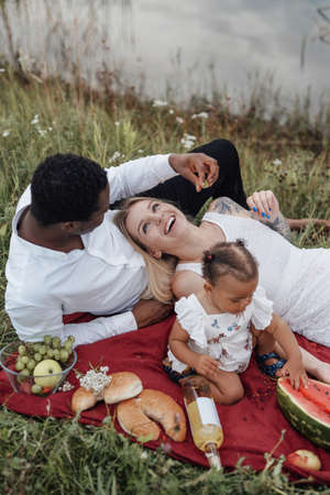 Little girl having picnic with her father and mother outdoorsの写真素材