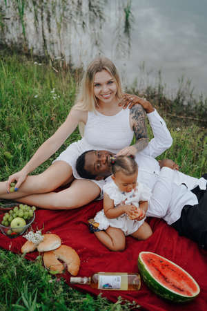 Mixed race family having picnic outdoors around riverの写真素材