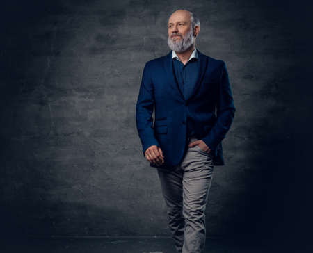 Elegant old man dressed in dark blue jacket against dark background