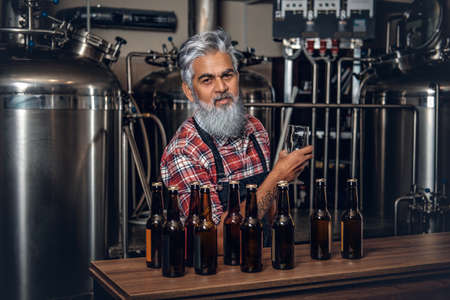 Elderly man producing quality beer in modern brewery