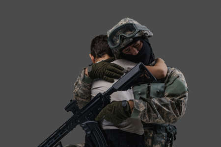 Army man embracing little kid isolated on gray background