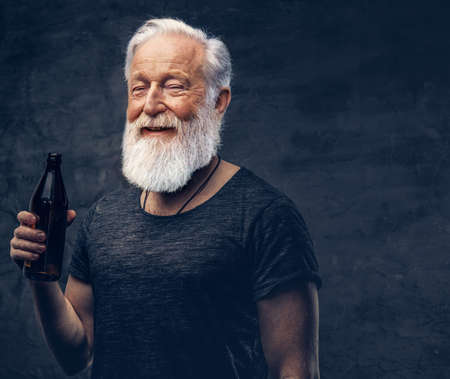 Joyful old man with bottle posing against dark background