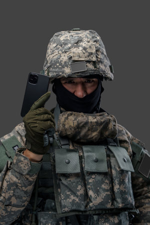 Serious ukrainian serviceman with cellphone looking at cameraの写真素材