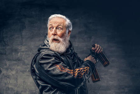 Amused grandfather biker holding two bottles against dark background