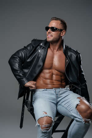 Stylish muscular guy dressed in jeans and leather jacketの写真素材