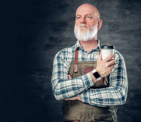 Old man barman with coffee cup against dark backgroundの写真素材