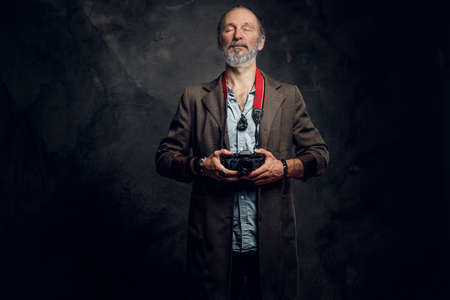 Spiritaul elderly man photographer posing against dark backgroundの写真素材