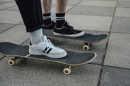 Shot of two skaters standing on skateboards on sidewalk