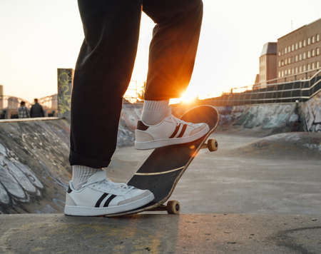 Trendy guy skater posing at skatepark at sunsetの写真素材