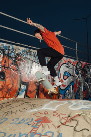 Skilled guy skateboarding at skate park at night time