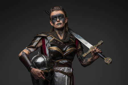 Warrior woman with sword and helmet against grey backgroundの写真素材