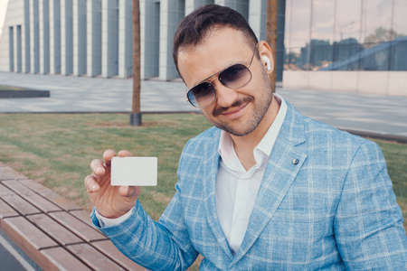 Joyful businessman with credit card looking at camera outdoorsの写真素材