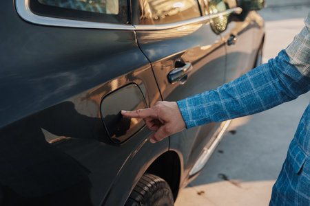 Man driver opening tank of his car outdoors in city