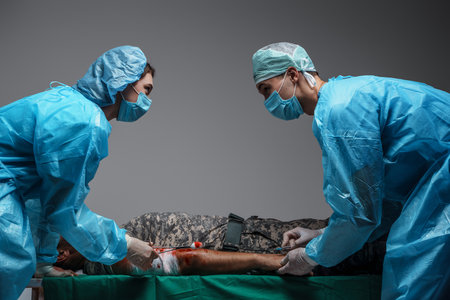 Surgeon and his assistant treating injured soldier in operating roomの写真素材