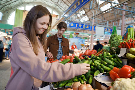 Happy couple of man and woman byuing vegetables in marketplaceの写真素材