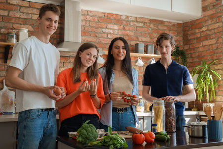 Four friends with vegetables cooking pizza at homeの写真素材
