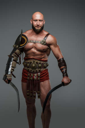 Strong greek warrior with swords against gray background