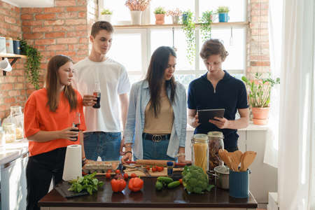Four friends cooking home pizza and celebrating event together