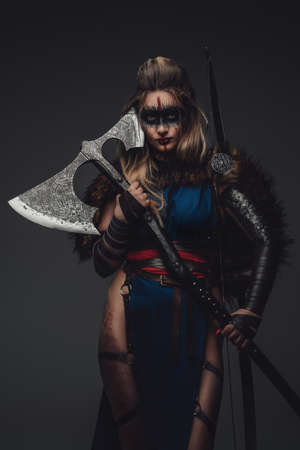 Female hunter with axe and bow against grey backgroundの写真素材