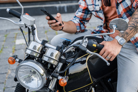 Tattooed biker using his cellphone driving bike outdoors