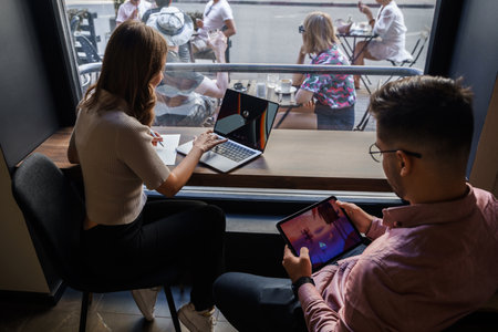 Couple of woman and man with laptop and tablet in coffee bar