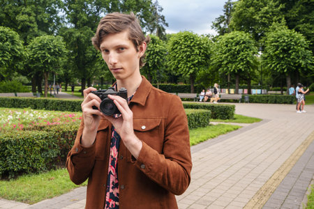 Young guy with photo camera walking in summer public park