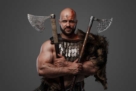 Bearded viking holding axes in cross against gray backgroundの写真素材