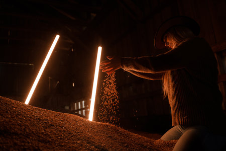 Woman farmer around led lamps and grain mountainの写真素材